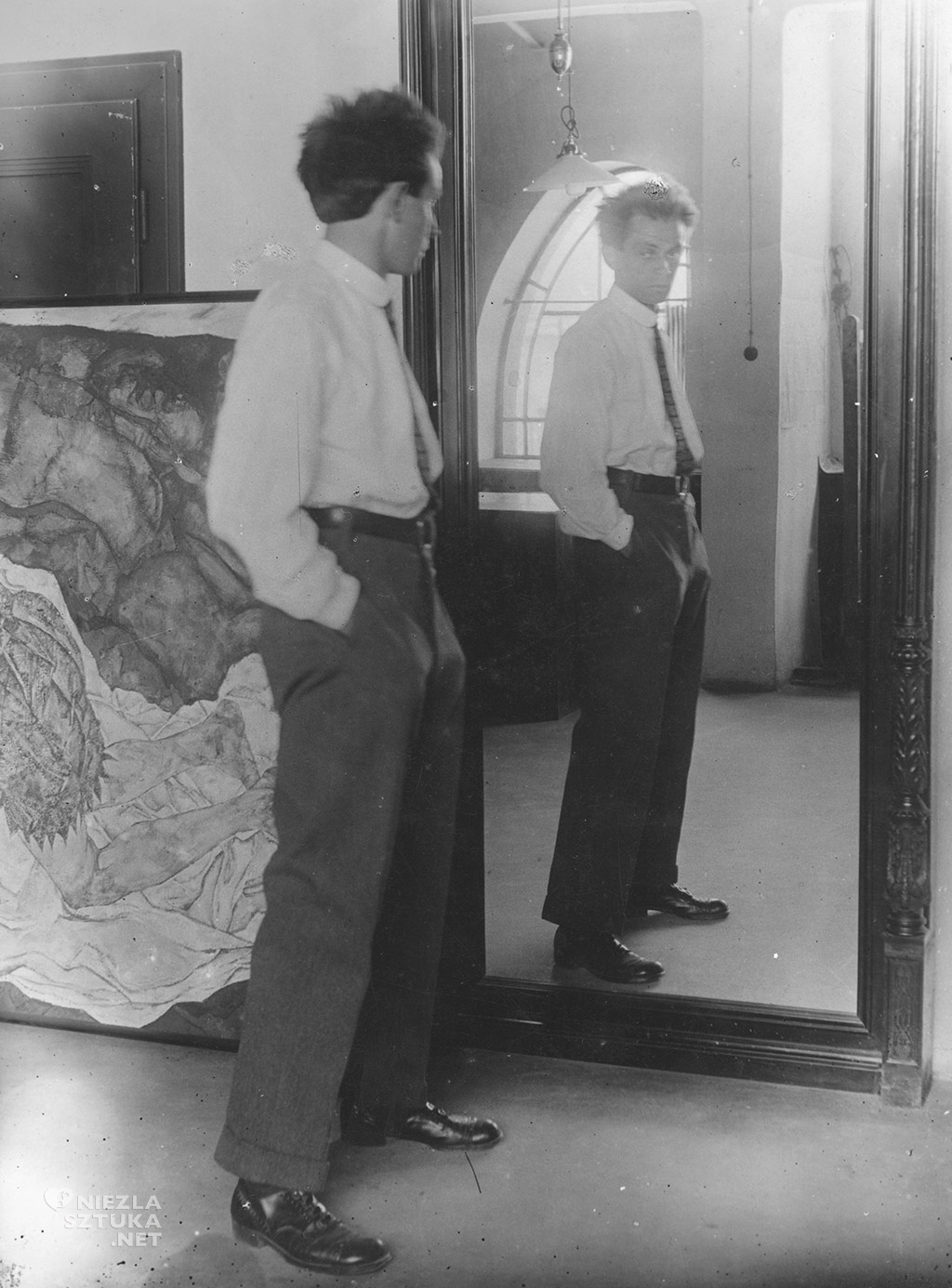 Egon Schiele, Portrait of Egon Schiele in front of his mirror in his Hietzing Atelier, in the backround the painting »Death and Girl« | 1915 Photography Leopold, Private collection